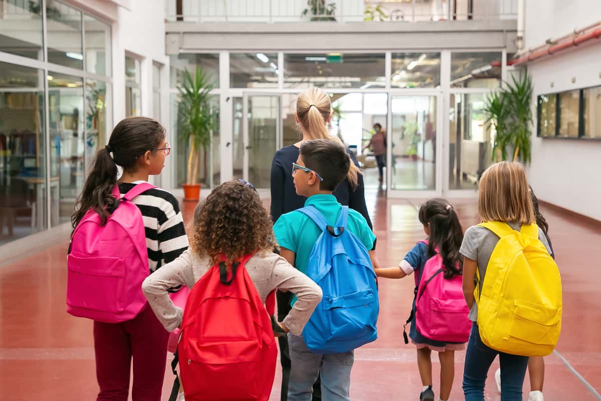 Ragazzini con lo zaino all'entrata di una scuola
